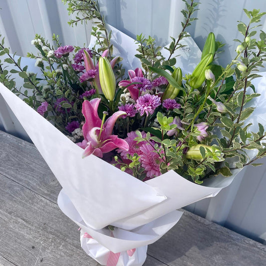 Vibrant Premium Seasonal Bouquet featuring lilies, chrysanthemums, and local natives, wrapped in brown paper with dual ribbons.