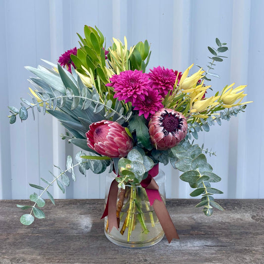 Vibrant Medium Native Arrangement featuring proteas, kangaroo paws, and colorful blooms in a 20cm glass with a ribbon.