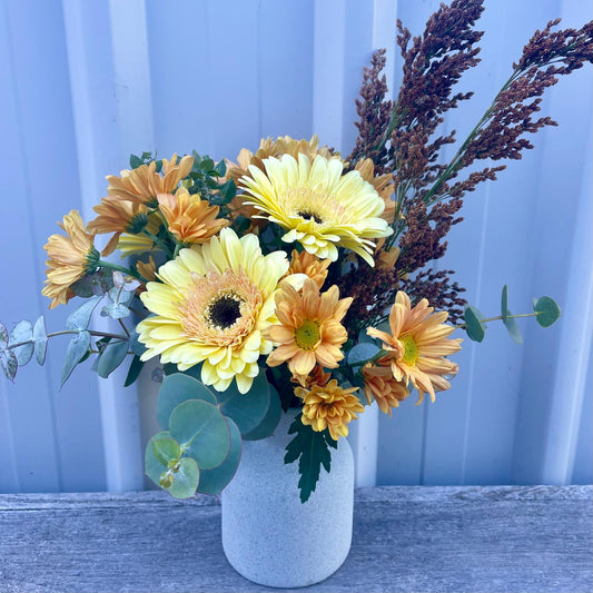 Vibrant spring flowers in a sleek white ceramic pot, showcasing a colorful Autumn Arrangement perfect for any space.