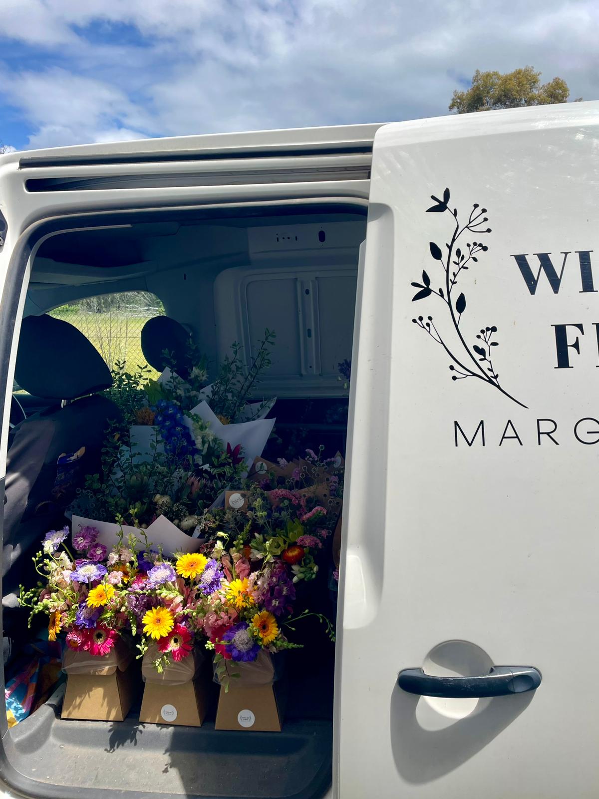 Van with "Wild Art Floral" branding and flowers showing behind the sliding door